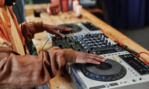 Hands of black man in casualwear standing by wooden table and creating new music and recording it for entertainment event